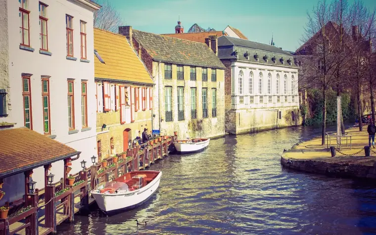 Un canal de Bruges bordé de maisons anciennes, deux barques amarrées