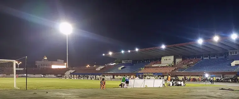Terrain de football sous les projecteurs, un soir, avec la tribune éclairée